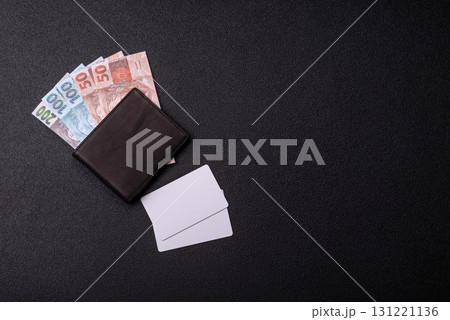 The white plastic card as a symbol of cashless payments on the background of cash paper money of Brazil 131221136
