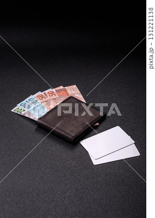 The white plastic card as a symbol of cashless payments on the background of cash paper money of Brazil 131221138