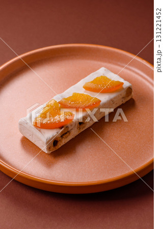 Nougat or white caramel with hazelnuts and pistachios and citrus pieces. White nougat with nuts 131221452