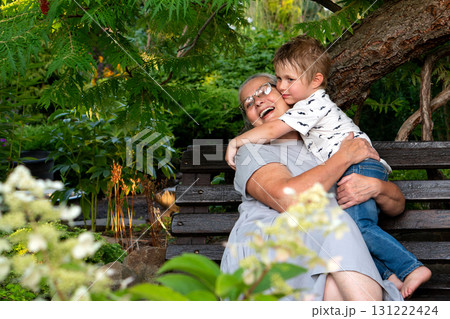 Grandmother hugging grandson happily on wooden bench Grandmother hugging grandson happily on wooden bench 131222424