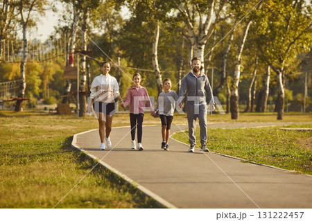 Family with children wearing sportswear holding hands walking together in the park. Family with children wearing sportswear holding hands walking together in the park. 131222457
