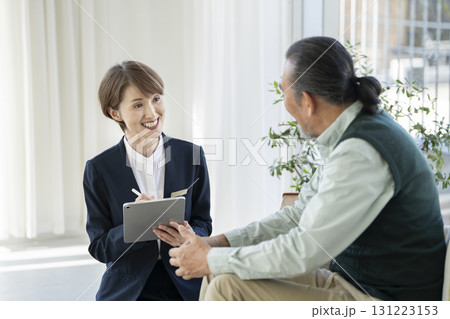 シニア男性と話すタブレットを持った女性施設スタッフ 131223153