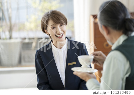 シニア男性と話すミドルの女性施設スタッフ 131223499