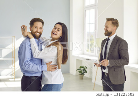 Happy woman is holding keys to newly purchased new house and hugging her husband. Happy woman is holding keys to newly purchased new house and hugging her husband. 131225502