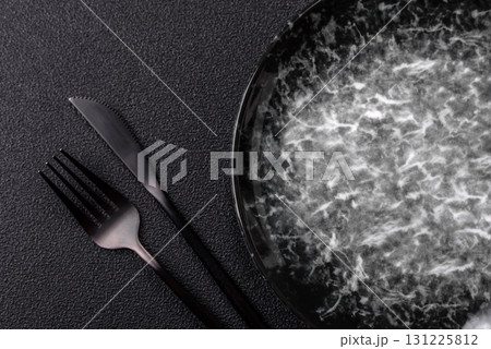 Empty round black plate for food, kitchen utensils on dining table. Empty plate Empty round black plate for food, kitchen utensils on dining table. Empty plate 131225812