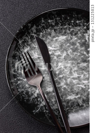 Empty round black plate for food, kitchen utensils on dining table. Empty plate Empty round black plate for food, kitchen utensils on dining table. Empty plate 131225813
