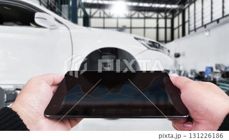 Mechanic using digital tablet with diagnostic graphs in modern auto repair shop Mechanic using digital tablet with diagnostic graphs in modern auto repair shop 131226186