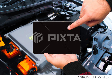 Mechanic using digital tablet with black blank screen to inspect electric vehicle battery system 131226187