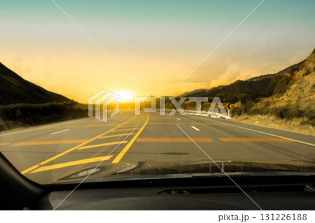 Driving on a scenic mountain road at sunset with golden sky, 131226188