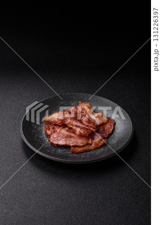 Cooked fried crispy bacon as an ingredient of a delicious English breakfast. Pieces of fried bacon Cooked fried crispy bacon as an ingredient of a delicious English breakfast. Pieces of fried bacon 131226397