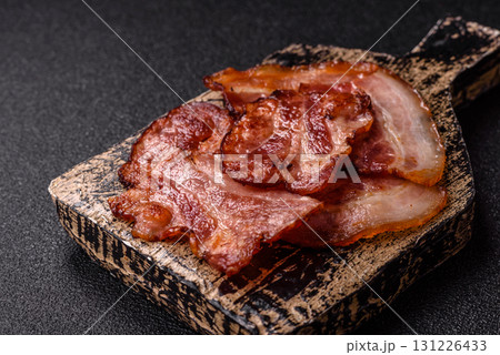 Cooked fried crispy bacon as an ingredient of a delicious English breakfast. Pieces of fried bacon 131226433