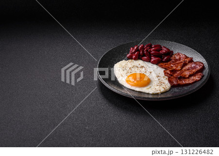 Fried egg, bacon and beans, a classic British breakfast with tomatoes. Egg, bacon and beans Fried egg, bacon and beans, a classic British breakfast with tomatoes. Egg, bacon and beans 131226482