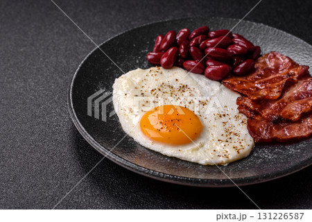 Fried egg, bacon and beans, a classic British breakfast with tomatoes. Egg, bacon and beans Fried egg, bacon and beans, a classic British breakfast with tomatoes. Egg, bacon and beans 131226587