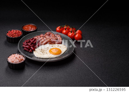 Fried egg, bacon and beans, a classic British breakfast with tomatoes. Egg, bacon and beans Fried egg, bacon and beans, a classic British breakfast with tomatoes. Egg, bacon and beans 131226595