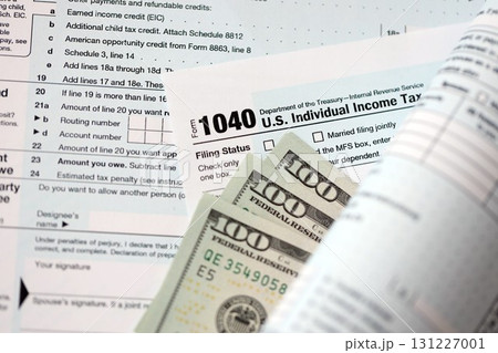 Hundred dollar bills and 1040 individual income tax return form blank close up 131227001