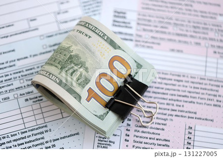 Big amount of United States dollar bills on table with 1040 tax return form Big amount of United States dollar bills on table with 1040 tax return form 131227005