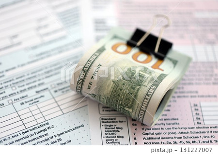 Big amount of United States USD dollar bills on table with 1040 tax return form Big amount of United States USD dollar bills on table with 1040 tax return form 131227007