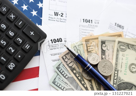 American US dollars money bills and coins with pen and calculator on IRS tax form blanks 131227021