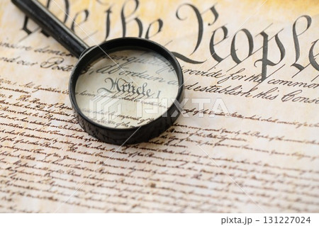 American USA Constitution paper page and magnifying glass close up 131227024