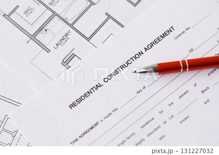 Pen on residential construction agreement and planning blueprints of residential building project 131227032