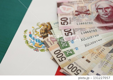 Mexican pesos money bills in big amount lies on Mexico flag close up Mexican pesos money bills in big amount lies on Mexico flag close up 131227057