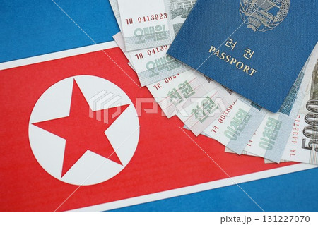 North Korean won money bills in big amount and passport lies on People Republic of Korea flag North Korean won money bills in big amount and passport lies on People Republic of Korea flag 131227070