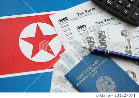 North Korean won money bills lies on table with pen, calculator, passport and tax forms 131227071
