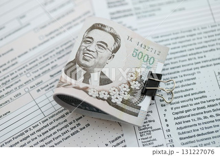 North Korean won money bills in big amount lies on table with tax forms close up North Korean won money bills in big amount lies on table with tax forms close up 131227076