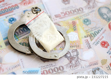 Vietnamese dong currency money bills and cocaine pack with handcuffs. The concept of drug crimes Vietnamese dong currency money bills and cocaine pack with handcuffs. The concept of drug crimes 131227215