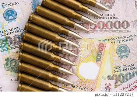 Vietnamese dong currency money bills and rifle bullets. The concept of warfare and gun selling Vietnamese dong currency money bills and rifle bullets. The concept of warfare and gun selling 131227217