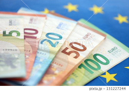 European eur currency money bills on Euro union blue flag close up European eur currency money bills on Euro union blue flag close up 131227244