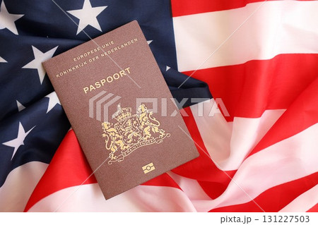 Netherlands passport on big waving flag of United States of America. US Visa and immigration 131227503