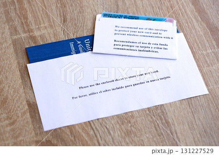 Permanent resident green card in envelope and guide for new immigrants lies on wooden table 131227529
