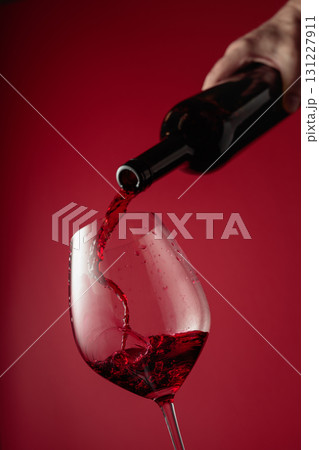 Pouring red wine from a bottle into a glass. 131227911