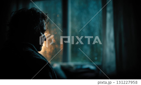 Seasonal depression. Person gazes out rain streaked window, illuminated by soft, moody lighting, creating contemplative atmosphere 131227958