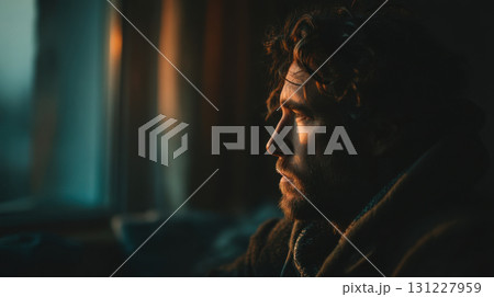 Seasonal depression. Thoughtful man gazes out window, bathed in warm, soft light, creating contemplative mood 131227959