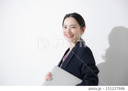 パソコン持ってスーツを着た立つ若いかわいい女性のビジネス上半身　かわいい白背景の営業 131227986