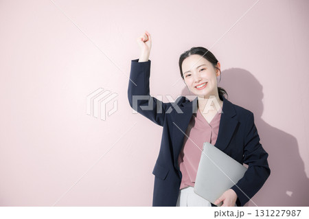 パソコン持ってスーツを着た立つ若いかわいい女性のビジネス上半身 ガッツポーズ パソコン持ってスーツを着た立つ若いかわいい女性のビジネス上半身 ガッツポーズ 131227987