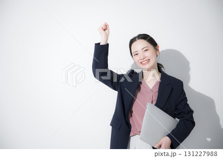 パソコン持ってスーツを着た立つ若いかわいい女性のビジネス上半身　ガッツポーズ　 131227988