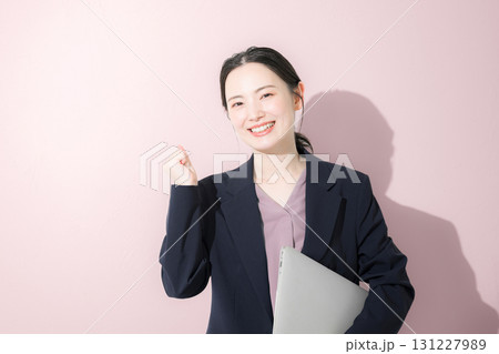 パソコン持ってスーツを着た立つ若いかわいい女性のビジネス上半身 ガッツポーズ パソコン持ってスーツを着た立つ若いかわいい女性のビジネス上半身 ガッツポーズ 131227989
