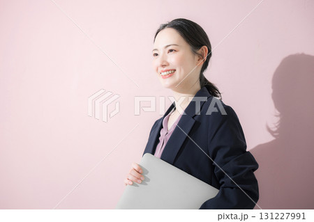 パソコン持ってスーツを着た立つ若いかわいい女性のビジネス上半身 見上げる パソコン持ってスーツを着た立つ若いかわいい女性のビジネス上半身 見上げる 131227991