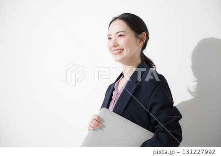 パソコン持ってスーツを着た立つ若いかわいい女性のビジネス上半身 見上げる パソコン持ってスーツを着た立つ若いかわいい女性のビジネス上半身 見上げる 131227992