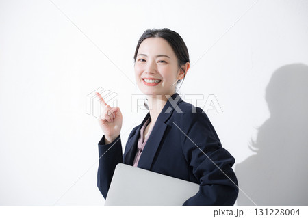 パソコン持ってスーツを着た立つ若いかわいい女性のビジネス上半身　かわいい営業など 131228004