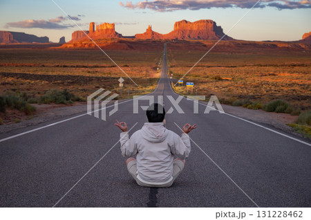 Rear view of tourist sitting on highway US route 163 looking at view of Monument Valley, Utah, USA Rear view of tourist sitting on highway US route 163 looking at view of Monument Valley, Utah, USA 131228462