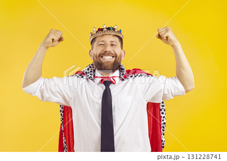 Portrait of young happy man in suit with crown looking at camera like a winner on yellow background Portrait of young happy man in suit with crown looking at camera like a winner on yellow background 131228741