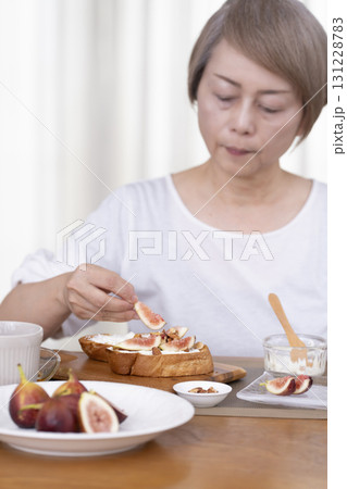 朝食のパンを食べるシニア女性 アウトフォーカス 朝食のパンを食べるシニア女性 アウトフォーカス 131228783