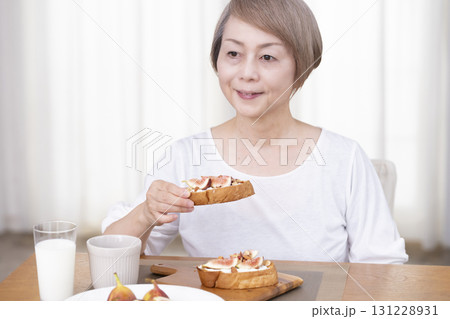 朝食のパンを食べるシニア女性 朝食のパンを食べるシニア女性 131228931