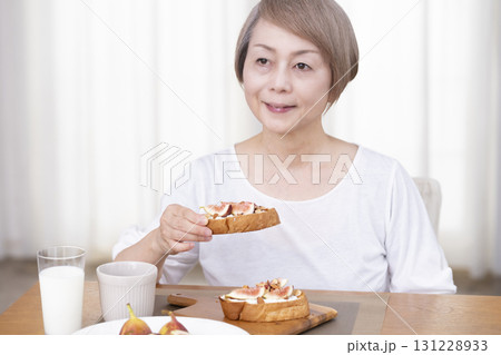 朝食のパンを食べるシニア女性   131228933