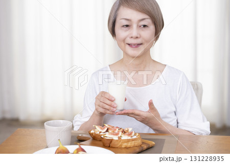 朝食のパンを食べるシニア女性   131228935