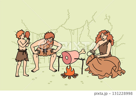Family primitive people stands around fire in forest, roasting meat for dinner or sewing up clothes 131228998